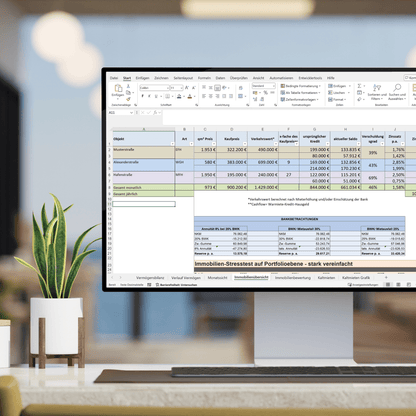 Ein Computerbildschirm zeigt eine Excel-Tabelle, die einen vereinfachten Immobilien-Stresstest auf Portfolioebene darstellt. Verschiedene Immobilienobjekte werden nach Kaufpreis, Verkehrswert und Kreditverlauf analysiert. Eine Tabelle im unteren Bereich zeigt Berechnungen zu Bankverträgen und Zinszahlungen. Im Vordergrund steht eine Zimmerpflanze, während der Hintergrund eines modernen Büros leicht unscharf ist.